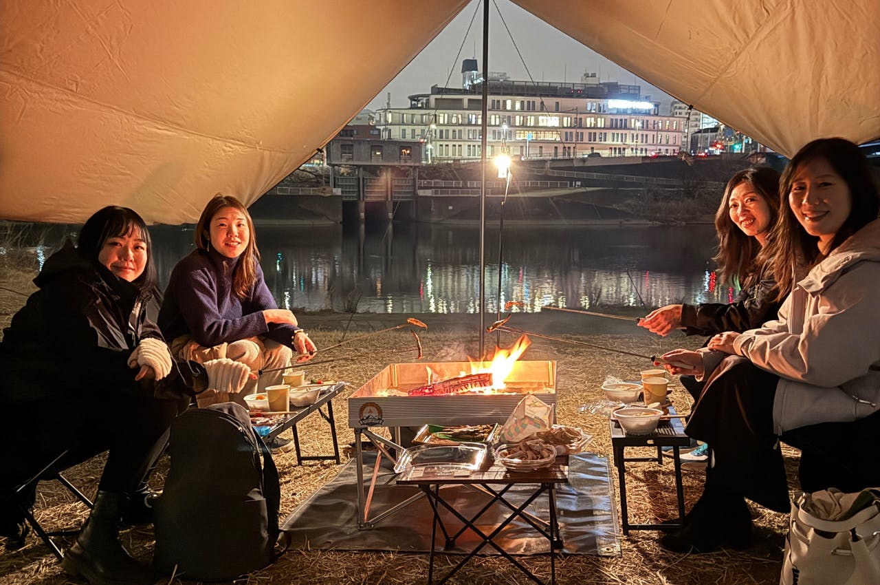 手ぶらで焚き火を囲む女性