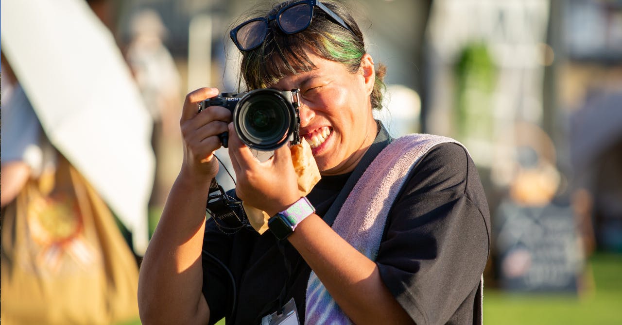 西宮市で開催された野外イベントにて、カメラを構えて笑顔で撮影する女性。
