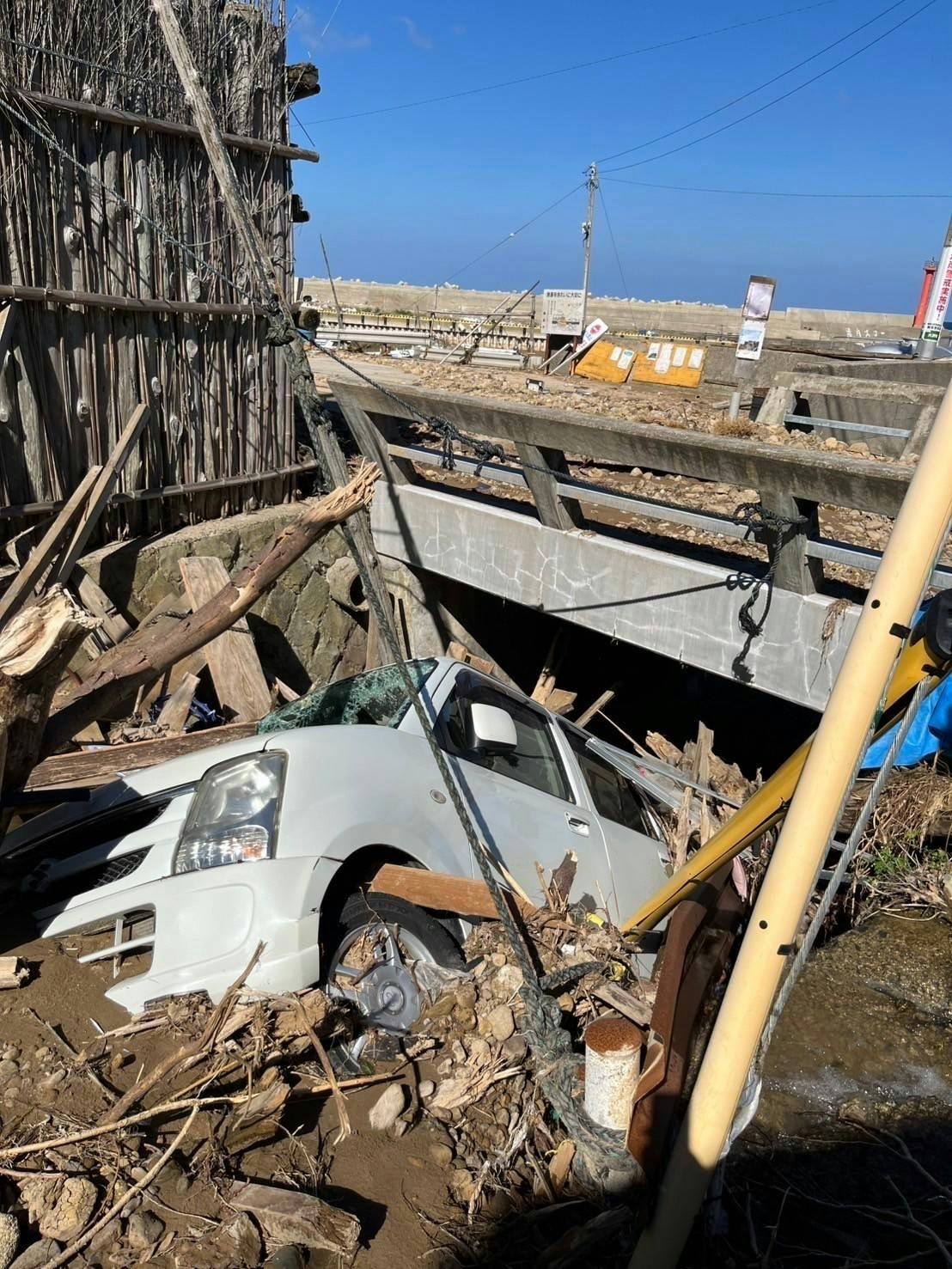 水害後の橋の下には白い車が流され挟まっている