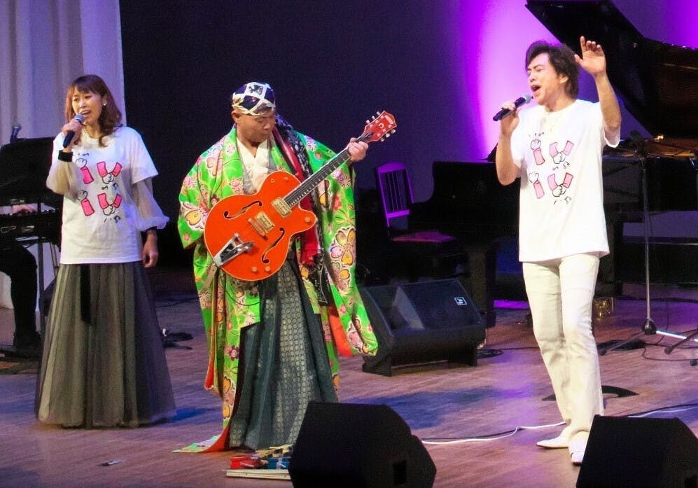 左　麻生かほ里　片腕のギタリスト輝彦　石井一孝の３人の写真