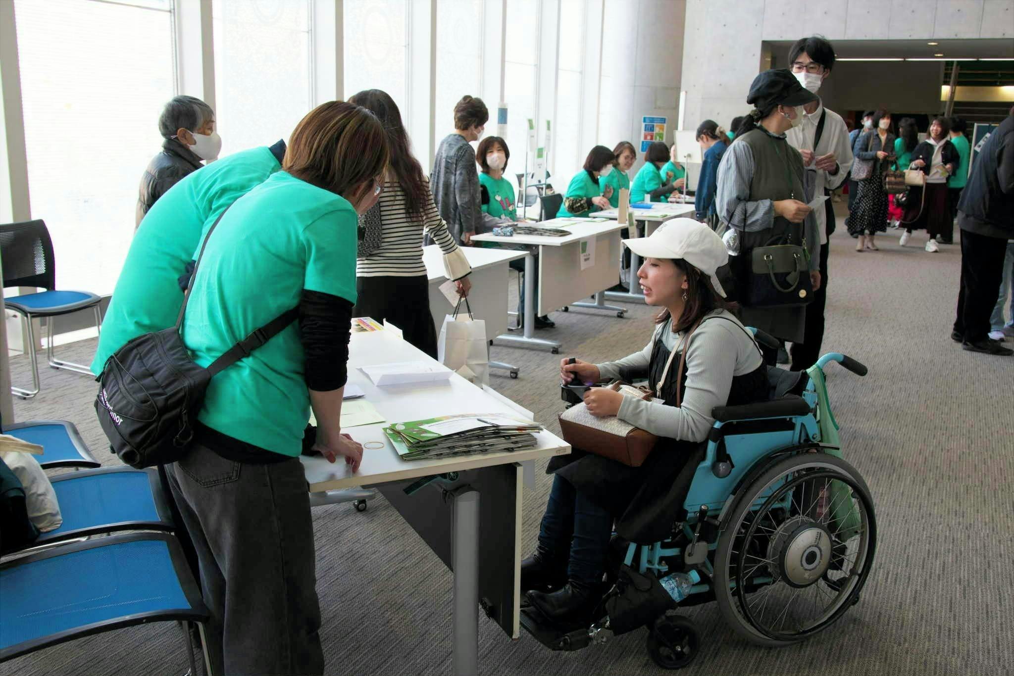 車椅子の女性に対応する受付スタッフの写真